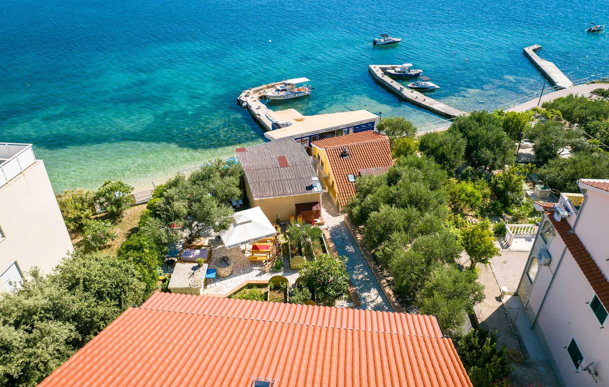 A coastal property with a clear view of the sea, a dock with boats, and a small outdoor seating area.