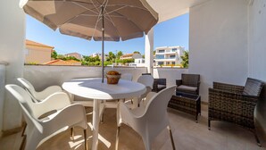 A balcony with a round table, white chairs, a wicker sofa, and a beige umbrella. - Cozy apartment in Barbat na Rabu with WiFi (Barbat na Rabu)