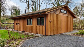 Une cabane en bois avec un toit en pente, deux fenêtres et un petit porche.