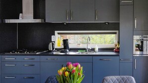 Une cuisine moderne avec des meubles de couleur sombre, une fenêtre et un vase de tulipes sur la table.