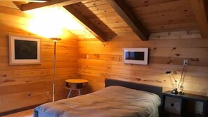A cozy bedroom with a bed, a small round table, and a desk with a lamp. - Goose Lake Cabin - two lakes to enjoy! (Spooner)