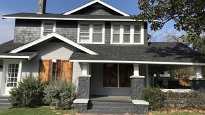 Une maison à deux étages avec un porche à l’avant, une cheminée et un garage.