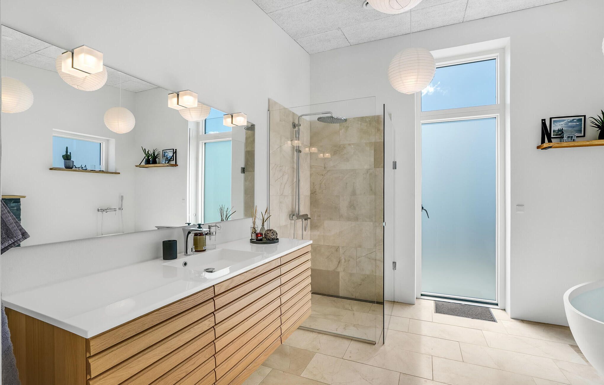 Une salle de bain moderne avec un grand miroir, une douche et une baignoire.