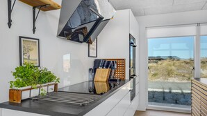 Una cucina moderna con una grande finestra, un piano cottura integrato e un supporto in legno per piante.