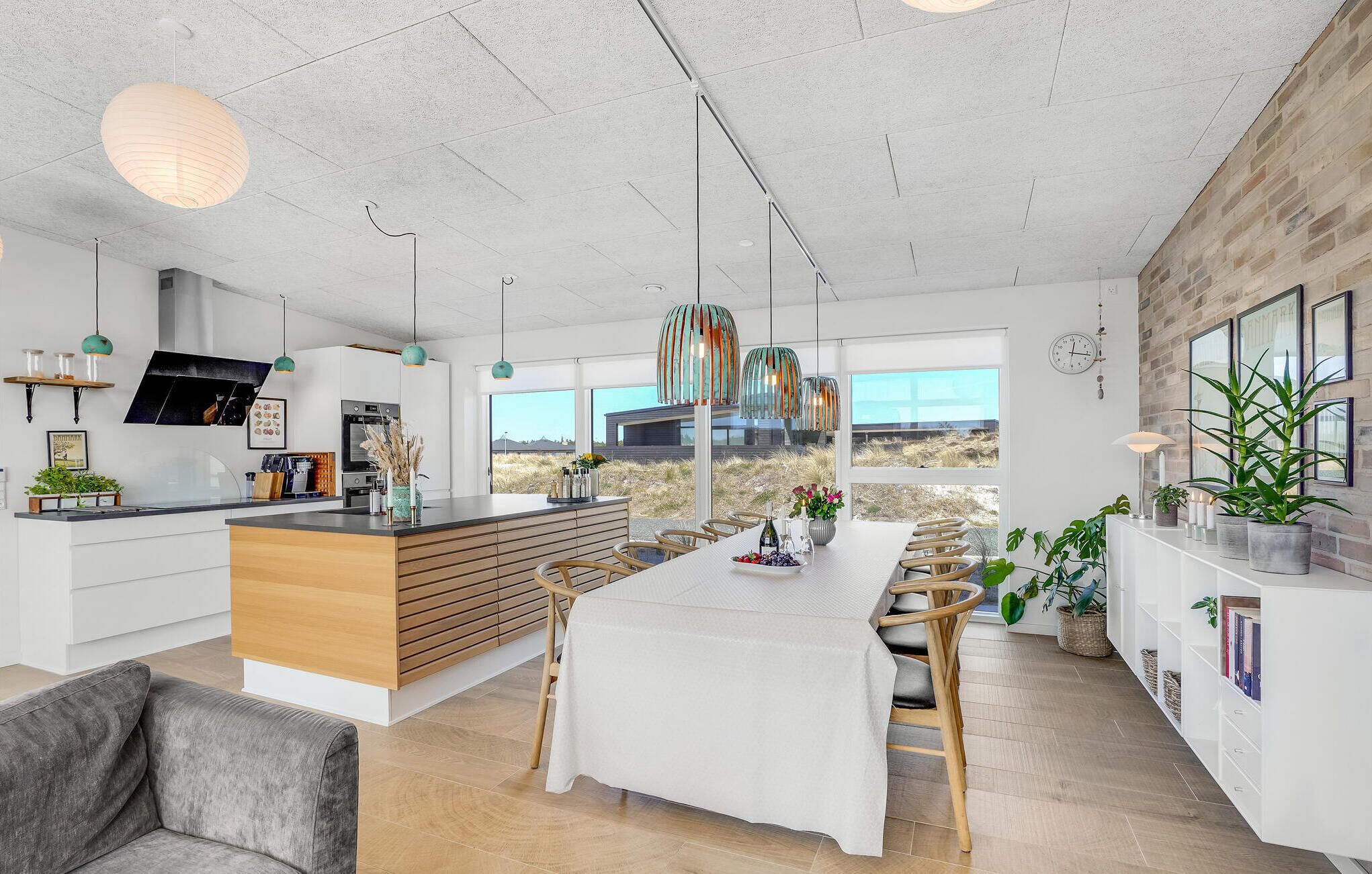 A modern kitchen with a central island, pendant lights, and a view of the desert landscape.