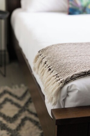 A neatly made bed with a beige blanket and a wooden headboard. - Bristol Gardens - Luxury Home, 2 min from the Beach (Brighton)