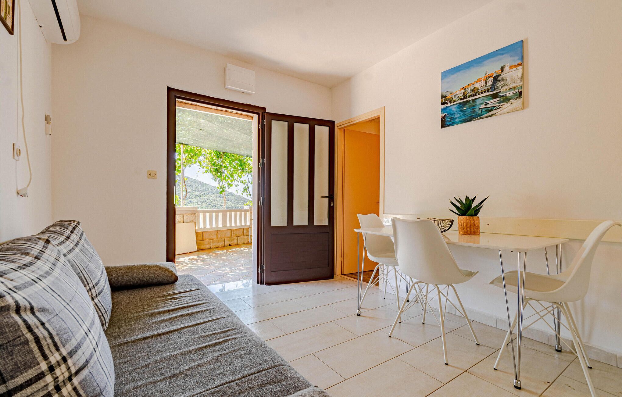 Un salon avec un canapé, un coin repas avec une table et des chaises, et une vue sur un balcon accessible par une porte.