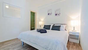 Un dormitori ben organitzat amb un llit, dues làmpades de nit, una tauleta de nit i una obra d'art penjada a la paret.