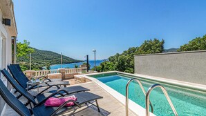 Una piscina al terrat amb gandules i vista al mar.