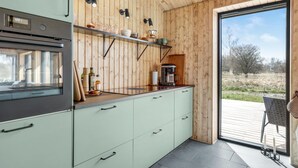 A modern kitchen with wooden paneling, a coffee maker, and a view of the outdoors.