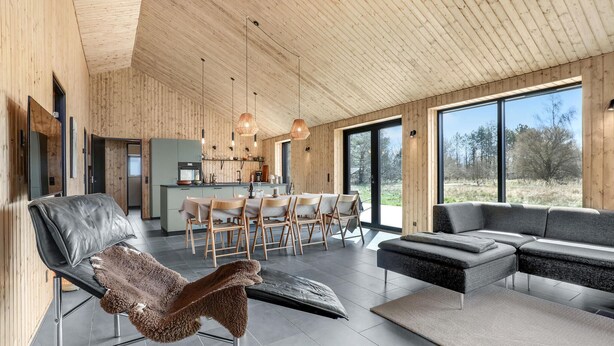 A modern interior with a dining area, kitchen, and seating space with large windows.