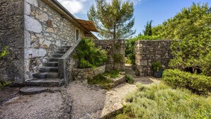 Un edificio de piedra con una escalera que conduce a una puerta, rodeado de follaje y árboles.