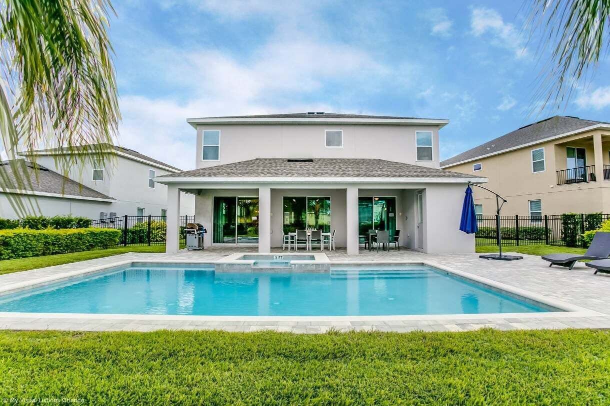 A two-story house with a swimming pool, a covered patio, and a fenced yard.