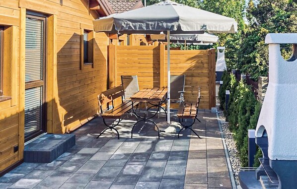 A wooden outdoor patio with a table and chairs, a covered umbrella, and a stone pathway.