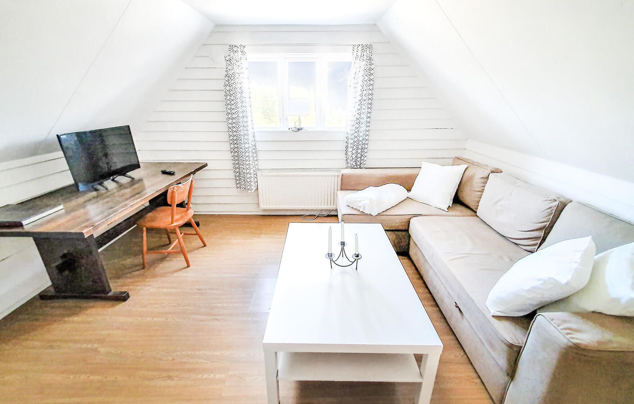 Une petite pièce lumineuse avec un lit en mezzanine, un bureau avec un ordinateur, un canapé et une table basse.