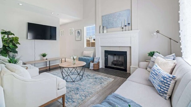 A modern living room with a fireplace, a flat-screen TV, and a sofa. - 5BR/3BA NEW Game Room, Pool + Arcade + Fire Pit! (Henderson)