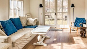 A cozy living room with a sofa, a coffee table, and a chair. There are two windows and a door leading outside. - Beautiful home in Löderup with kitchen (Löderup)