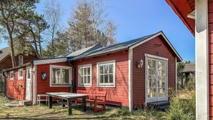 A red wooden house with two windows, a door, and a small table with a bench. - Beautiful home in Löderup with kitchen (Löderup)