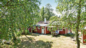 A small red cabin with a chimney, surrounded by trees and a grassy yard. - Beautiful home in Löderup with kitchen (Löderup)