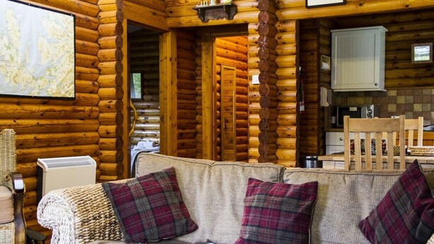 Ein rustikales Blockhaus-Interieur mit einer Sofagarnitur, einer Karte an der Wand und einem Küchenbereich.