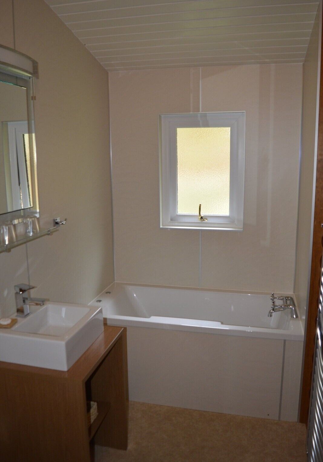 Une salle de bain avec un lavabo, un miroir et une fenêtre située au-dessus de la baignoire.
