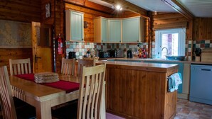 A cozy cabin-style kitchen with wooden cabinets, a dining table with chairs, and a small island with a sink.