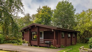 Een rustieke blokhut met een veranda, een klein terras en een picknicktafel.