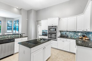 Enjoy cooking in this well-equipped kitchen with a central island, white cabinetry, and stainless steel appliances.