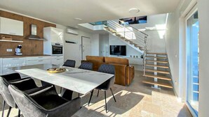 Una cucina moderna con zona pranzo, una scala e un soggiorno con divano.