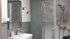 A modern bathroom with a glass-enclosed shower, a white sink, and a mirror.