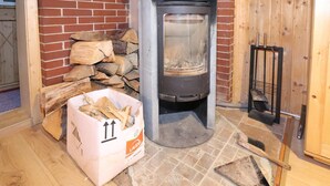 A wood stove with a brick wall and a tiled floor.