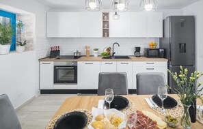 Una cucina moderna con mobili bianchi, forno integrato, microonde e frigorifero Samsung.
