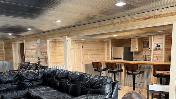 Ein modernes Interieur mit einem Ecksofa aus Leder, einem Essbereich mit Holzausbau und einer Küche mit Kühlschrank.