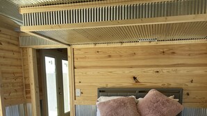 Ein Schlafzimmer mit einem hölzernen Kopfteil, einem großen Bett mit weißer Bettwäsche und einem rosa, flauschigen Kissen.