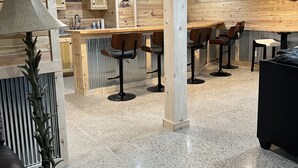 Ein modernes Interieur mit Barbereich, Holzwandverkleidung und einem polierten Steinboden.
