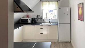 Eine kleine Küche mit Mikrowelle, Kaffeemaschine, Messern und Kühlschrank.