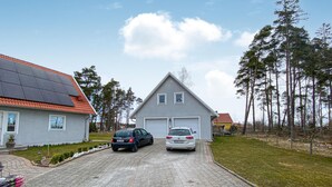 Ein zweistöckiges Haus mit Garage, Solaranlage auf dem Dach und zwei Autos auf der Auffahrt.