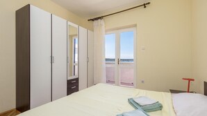 Slaapkamer met een bed, twee handdoeken, een kledingkast, een spiegel en een balkon met uitzicht.
