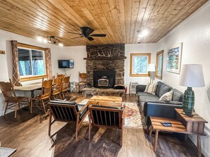 A cozy living room with a stone fireplace, wooden furniture, and a television mounted on the wall. - Croll Cabins-Brock Hillside -#3 at Vallecito Lake.  Secluded, newly remodeled! (Bayfield)