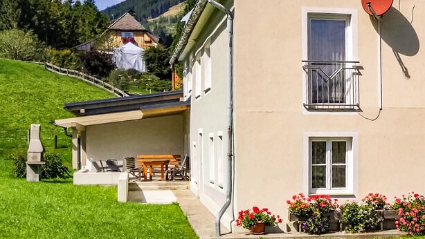 A two-story house with a balcony, a satellite dish, and a garden with potted flowers. - Ferienwohnung in Vordernberg (Vodernberg)