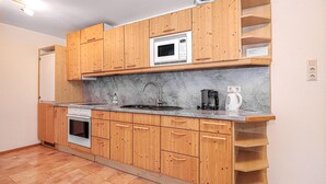 A kitchen with wooden cabinets, a built-in microwave, a stove, a sink, and a coffee maker. - Ferienwohnung in Vordernberg (Vodernberg)