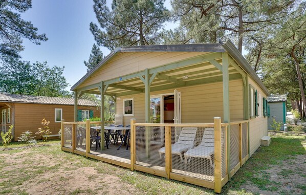Eine Holzjagdhaus mit überdachter Veranda, Sitzgelegenheiten im Freien und einem eingezäunten Bereich.