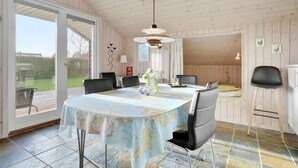 A dining area with a table covered by a map tablecloth, wooden walls, and a view of the outdoors. - Beautiful home in Sydals with WiFi (Sydals)