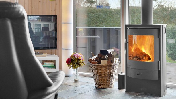 A modern living room with a large TV, a wicker basket, a vase of flowers, and a wood-burning stove. - Beautiful home in Sydals with WiFi (Sydals)