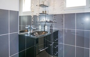 A modern bathroom with a black sink, chrome fixtures, and a glass shower enclosure. - Amazing home in Cruzy (Cruzy)