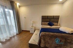 Une chambre d’hôtel avec un lit, une table de chevet, une lampe et des rideaux.