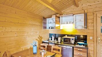 Une cuisine de taille réduite avec des murs en bois, une table à manger et les appareils électroménagers de base.