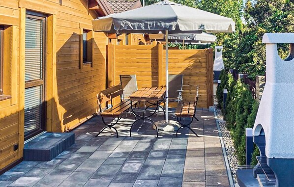 A wooden patio with a table and chairs, a covered umbrella, and a stone wall.