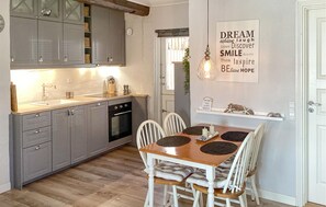 Enjoy meals in this kitchen with a dining table and four chairs, featuring a convenient countertop and a stylish light fixture.