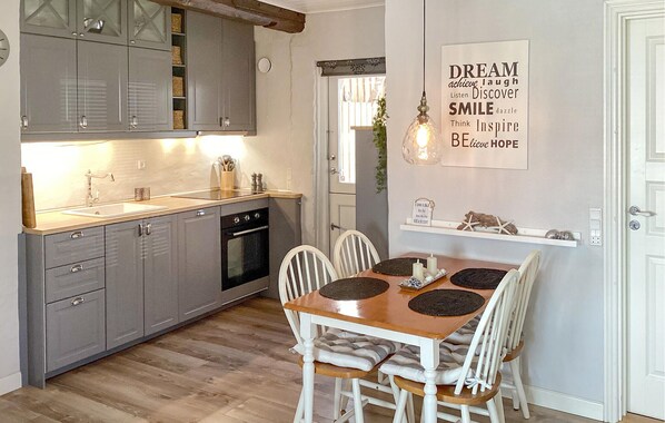 A modern kitchen with grey cabinets, a wooden countertop, and a dining area with a wooden table and white chairs. - Nice home in Sønderborg with WiFi (Sønderborg)